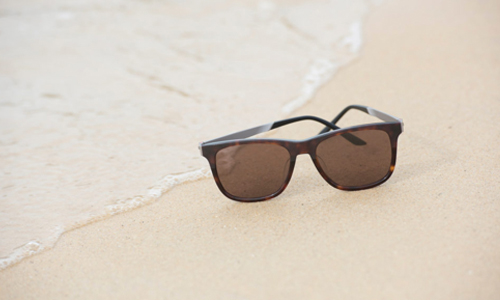 Paire de lunettes solaires posées sur la plage au bord de l'eau